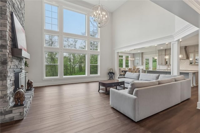 living room featuring a fireplace, a chandelier, a high ceiling, and wood finished floors