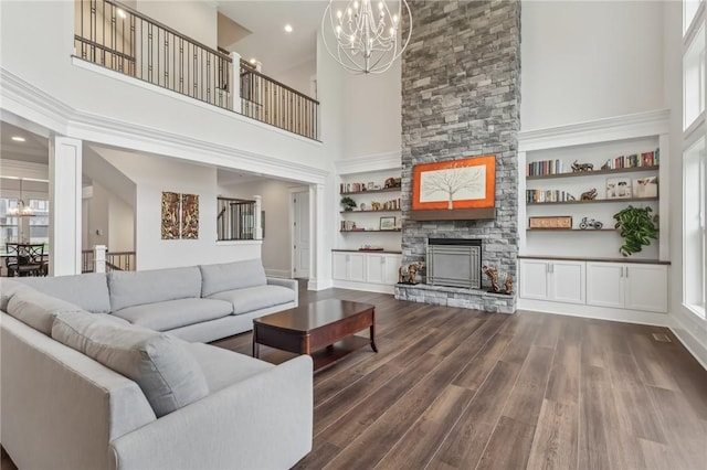 living area featuring a fireplace, an inviting chandelier, a towering ceiling, and dark wood-style floors