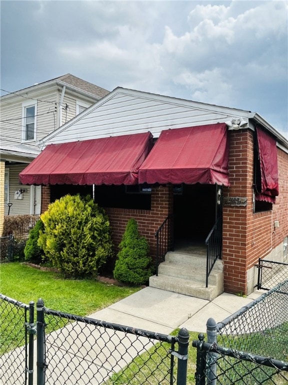 view of front of home with entry steps, fence, and brick siding