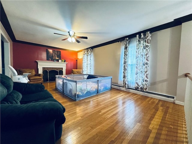 living area with ceiling fan, crown molding, hardwood / wood-style floors, and a baseboard heating unit