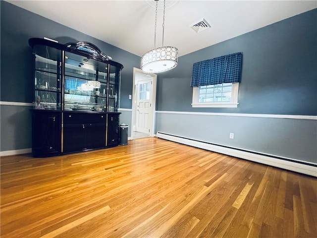 unfurnished dining area featuring baseboards, a baseboard radiator, visible vents, and wood finished floors