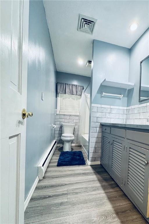 bathroom with toilet, wood finished floors, a baseboard radiator, visible vents, and vanity