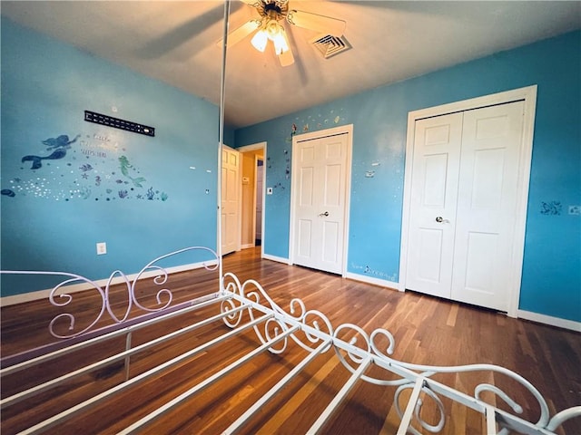 bedroom with baseboards, ceiling fan, visible vents, and wood finished floors