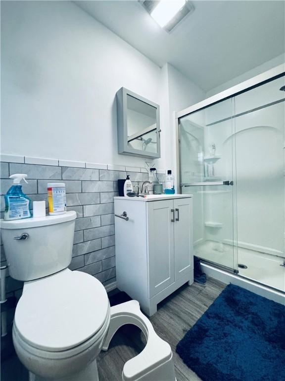 bathroom with toilet, tile walls, and wood finished floors