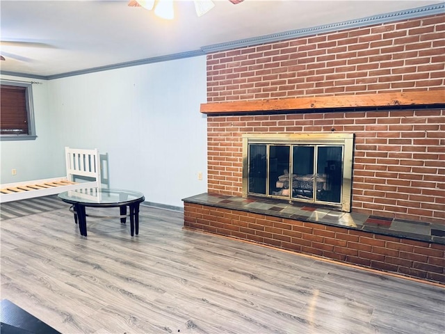 living area featuring ornamental molding, a brick fireplace, a ceiling fan, and wood finished floors