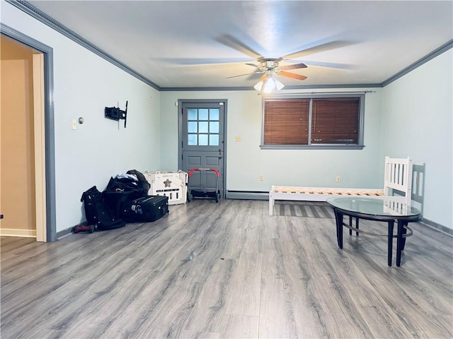 interior space with ceiling fan, wood finished floors, baseboards, and ornamental molding