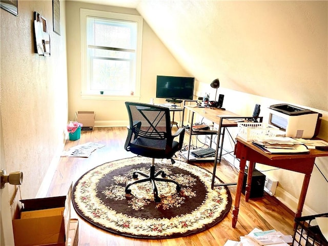 office space with vaulted ceiling, a textured wall, and wood finished floors