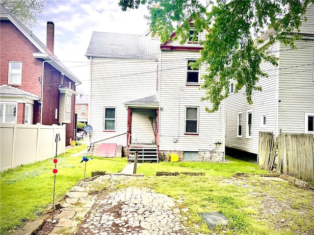 back of property with a lawn, roof with shingles, and fence
