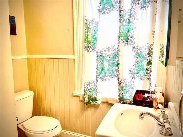 bathroom featuring a sink, wainscoting, and toilet