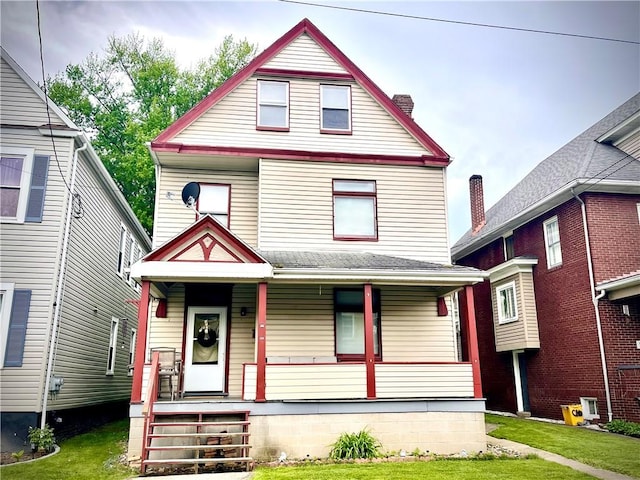 victorian home featuring a porch, a chimney, and a front yard