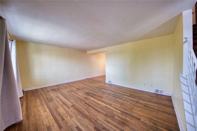 empty room featuring visible vents, wood finished floors, and baseboards