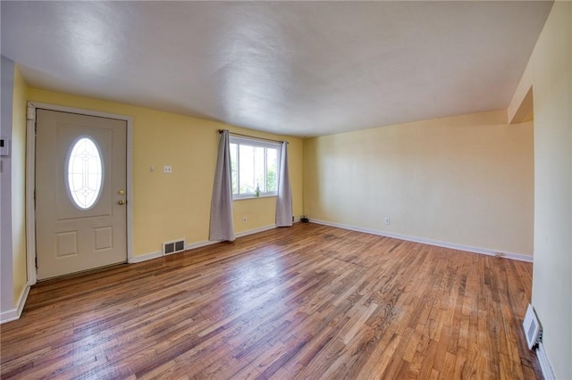 foyer entrance featuring baseboards, visible vents, and wood finished floors