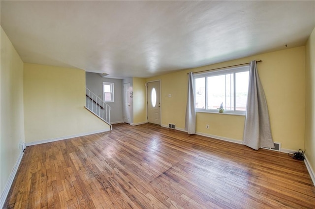 foyer with baseboards, stairway, visible vents, and wood finished floors