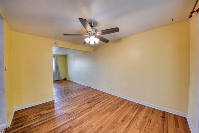 spare room featuring baseboards, light wood finished floors, and ceiling fan