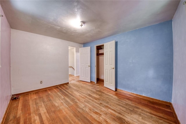 unfurnished bedroom with baseboards, a closet, and wood finished floors