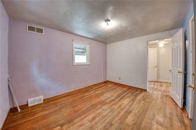 unfurnished bedroom featuring light wood finished floors, baseboards, and visible vents