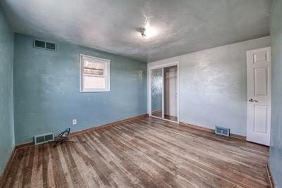 unfurnished bedroom featuring a closet, visible vents, and wood finished floors