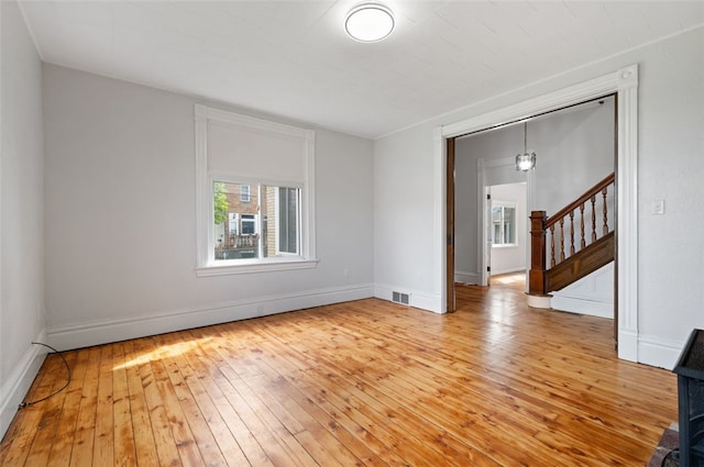 unfurnished room featuring stairs, baseboards, light wood-type flooring, and visible vents