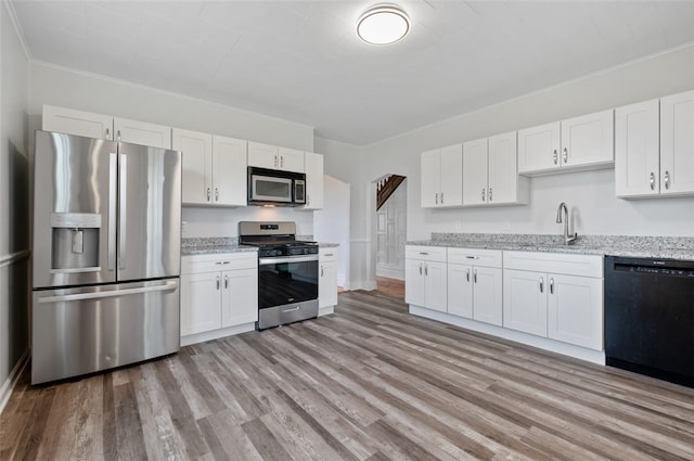 kitchen with white cabinetry, light wood-style floors, appliances with stainless steel finishes, and a sink