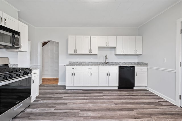 kitchen with a sink, stainless steel appliances, wood finished floors, ornamental molding, and white cabinetry