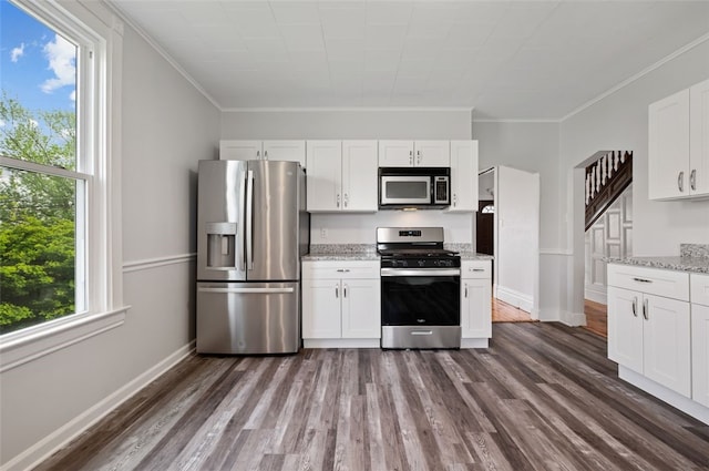 kitchen with crown molding, white cabinetry, dark wood-style flooring, light stone countertops, and appliances with stainless steel finishes