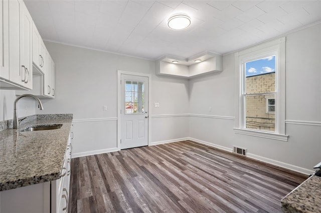 unfurnished dining area with a healthy amount of sunlight, dark wood finished floors, visible vents, and a sink