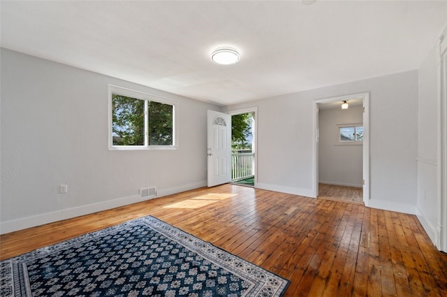 unfurnished room featuring baseboards, wood-type flooring, and visible vents