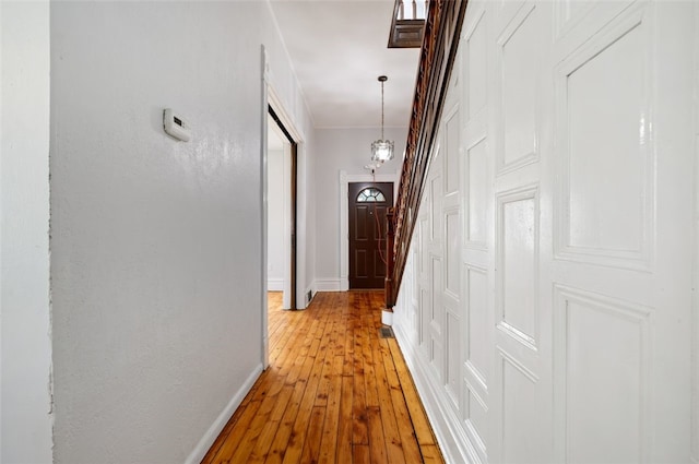 hallway with a barn door, light wood-style flooring, and baseboards