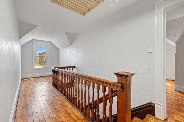 interior space featuring baseboards, an upstairs landing, wood-type flooring, and vaulted ceiling
