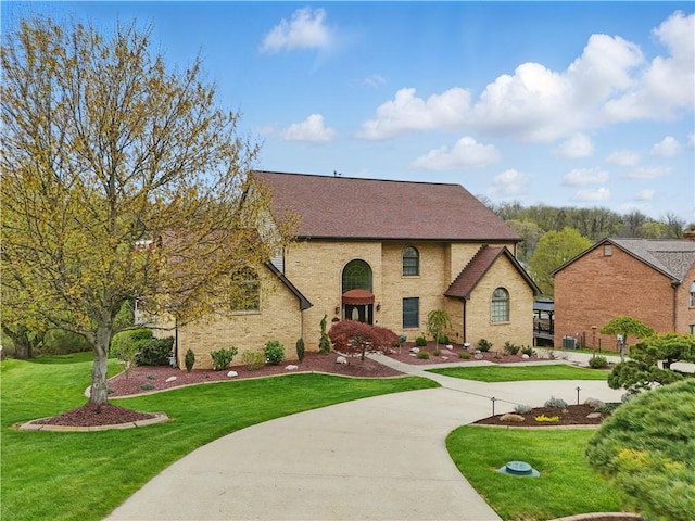 view of front of house with a front yard and a shingled roof