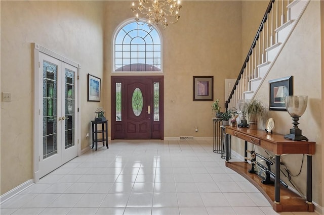 entryway featuring french doors, a chandelier, baseboards, and a high ceiling