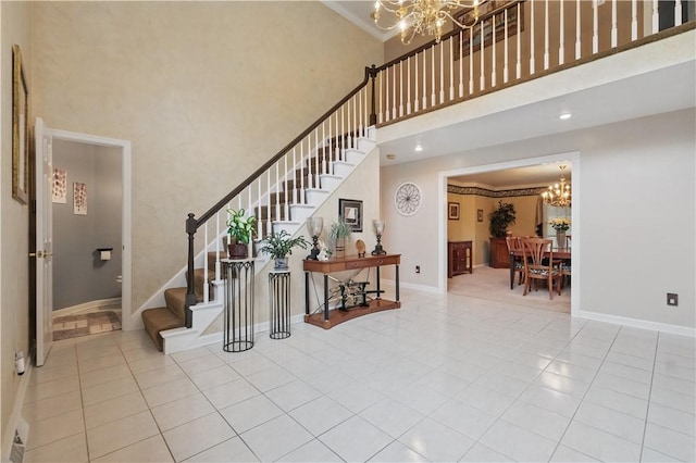stairs featuring a towering ceiling, a notable chandelier, baseboards, and tile patterned floors
