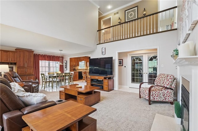 living room with french doors, visible vents, crown molding, a fireplace with flush hearth, and light carpet