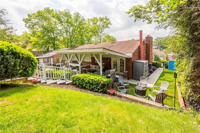 1306 Cochran Rd, Mt Lebanon, PA 15243 - back of property with an outdoor living space with a fire pit, a lawn, and brick siding