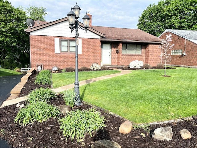 view of front of property featuring a front lawn, brick siding, and a chimney