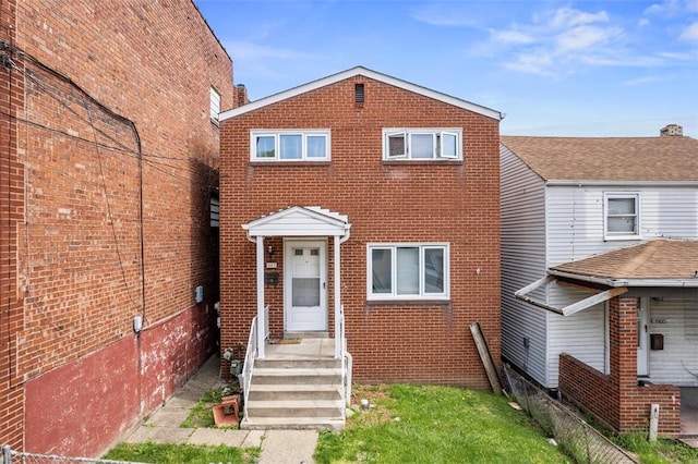 view of front facade featuring brick siding and fence