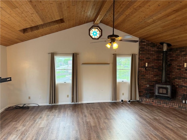 unfurnished living room with a wood stove, a wealth of natural light, wood finished floors, and a ceiling fan