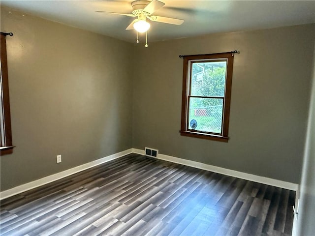 spare room with dark wood finished floors, visible vents, baseboards, and a ceiling fan