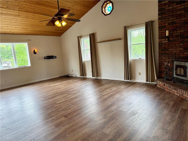 unfurnished living room featuring a wood stove, wood ceiling, wood finished floors, and a healthy amount of sunlight