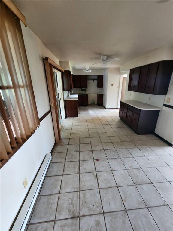 219 Meadow Dr, Westmont Hilltop School District, PA 15905 - kitchen with baseboard heating, light tile patterned floors, ceiling fan, dark brown cabinetry, and light countertops