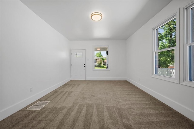 carpeted empty room featuring baseboards and visible vents