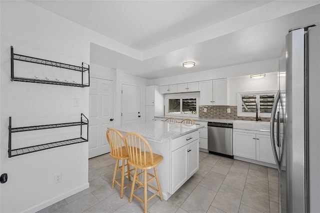 kitchen with white cabinets, appliances with stainless steel finishes, light tile patterned flooring, and a kitchen breakfast bar
