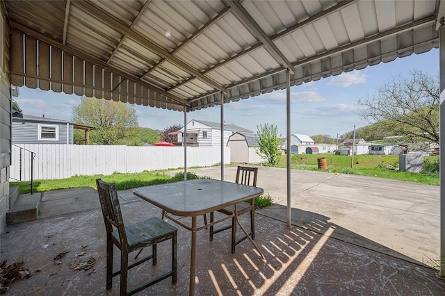view of patio / terrace with a residential view, outdoor dining space, a storage unit, fence, and an outbuilding