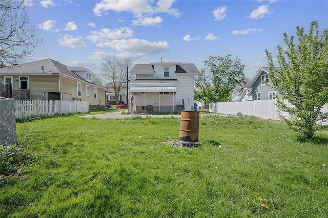 back of house featuring a yard, fence, and a residential view
