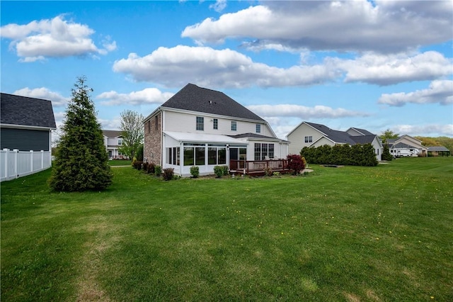 back of house with a sunroom, a yard, a deck, and fence