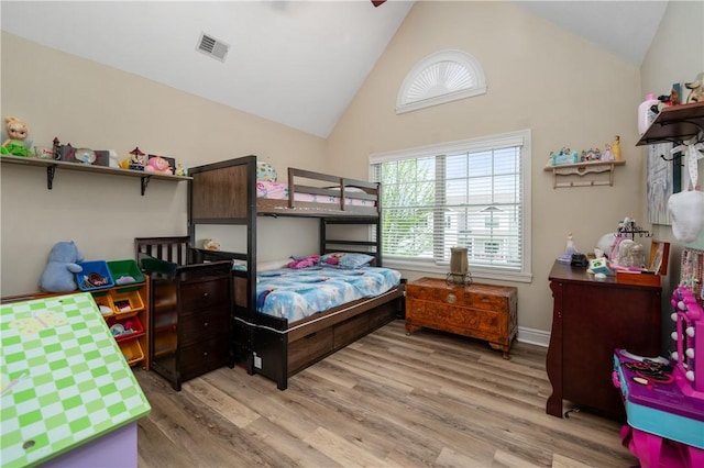 bedroom with light wood-style flooring, visible vents, and high vaulted ceiling