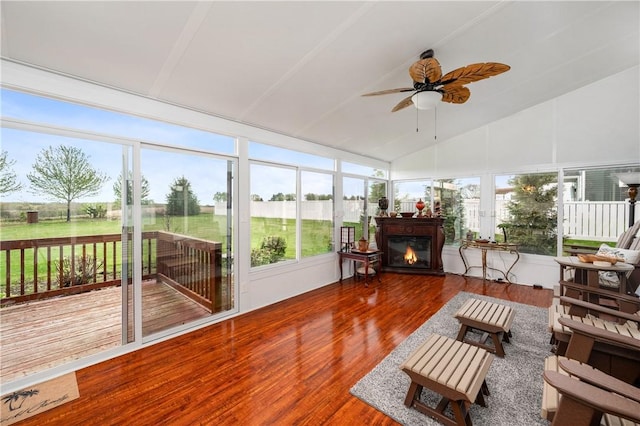 sunroom / solarium with vaulted ceiling, a wooden deck, plenty of natural light, and wood finished floors