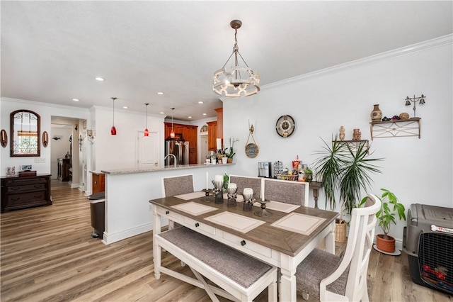 dining space with crown molding, a chandelier, light wood-style flooring, and recessed lighting