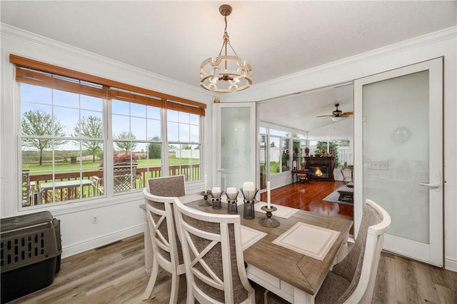 dining area with a wealth of natural light, ornamental molding, and a glass covered fireplace