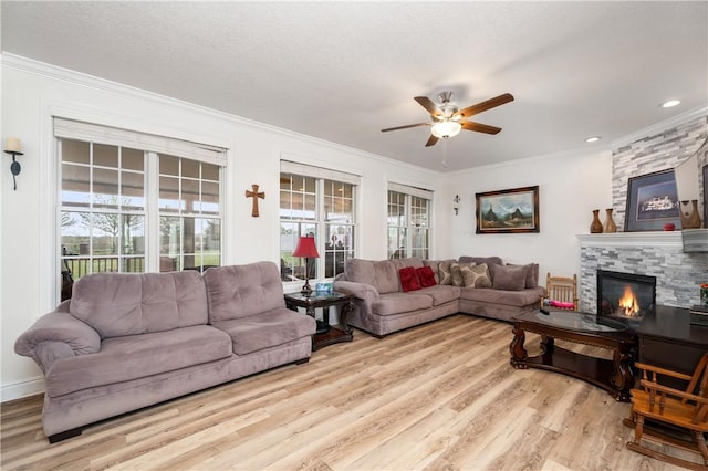 living area featuring a ceiling fan, a wealth of natural light, light wood finished floors, and crown molding
